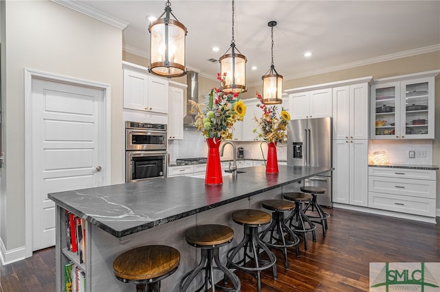 kitchen with white cabinets, a kitchen island with sink, decorative backsplash, and stainless steel appliances