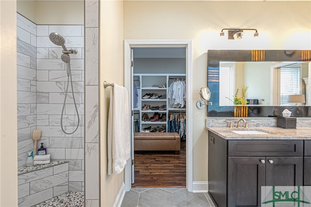 bathroom featuring vanity, a tile shower, and tile patterned flooring