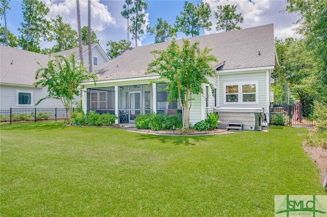 back of house featuring a lawn, a hot tub, and a sunroom