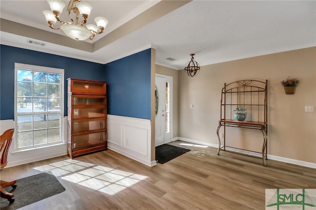 foyer entrance featuring crown molding, an inviting chandelier, and light hardwood / wood-style floors