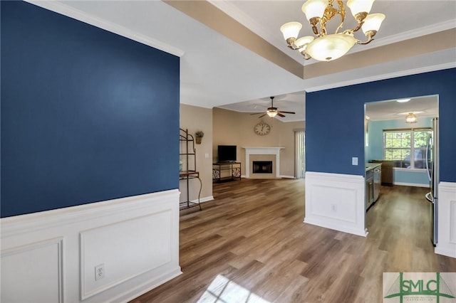 interior space featuring ceiling fan with notable chandelier, wood-type flooring, and crown molding