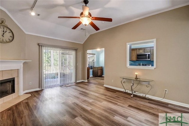 unfurnished living room with lofted ceiling, crown molding, a fireplace, and hardwood / wood-style floors