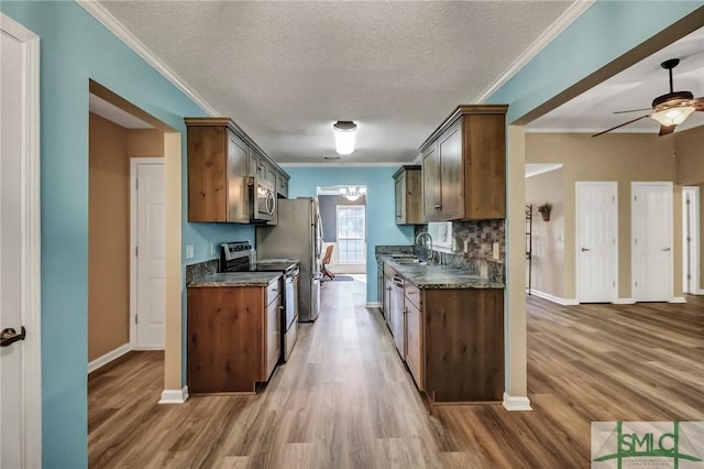 kitchen with appliances with stainless steel finishes, decorative backsplash, dark stone counters, a textured ceiling, and sink