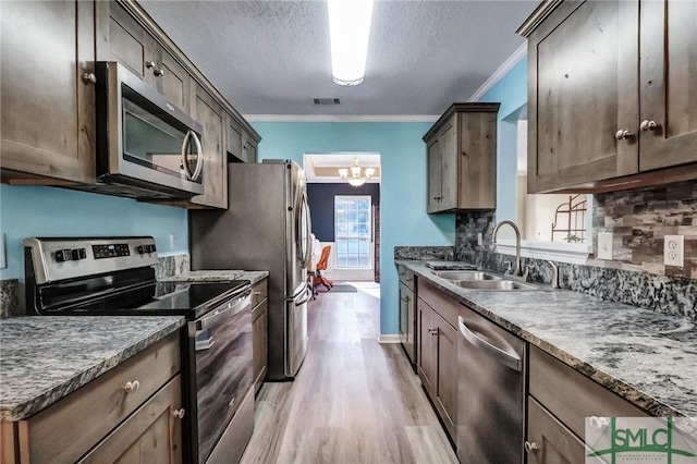kitchen with decorative backsplash, sink, light hardwood / wood-style flooring, stainless steel appliances, and ornamental molding