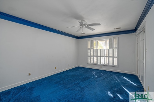 empty room featuring dark colored carpet, crown molding, and ceiling fan