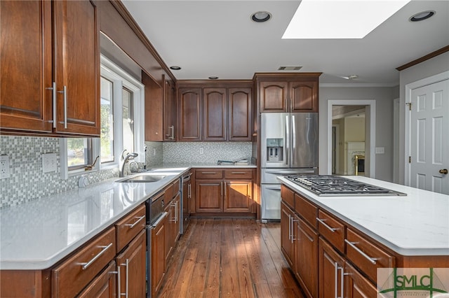 kitchen featuring a center island, sink, a skylight, stainless steel appliances, and ornamental molding