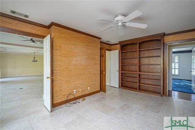 spare room featuring ceiling fan, crown molding, and wooden walls