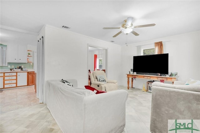 living room with ceiling fan, crown molding, and light tile patterned flooring