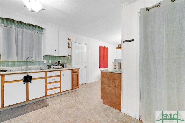 kitchen with crown molding, white cabinets, tasteful backsplash, and sink