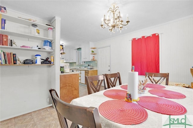 dining area with sink, ornamental molding, and a chandelier