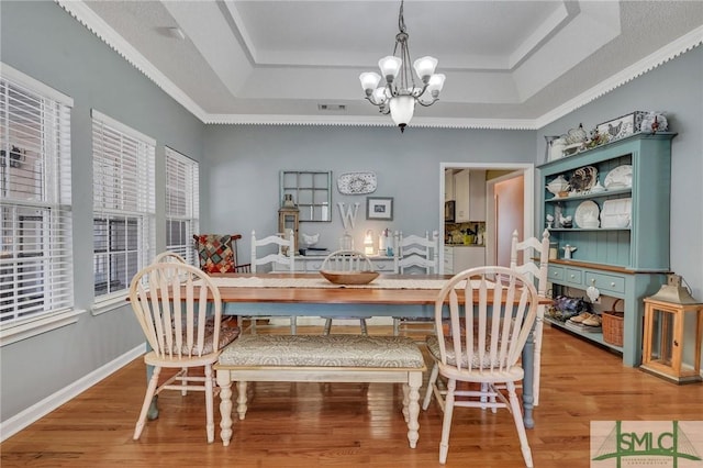 dining room featuring hardwood / wood-style floors, a chandelier, and a raised ceiling