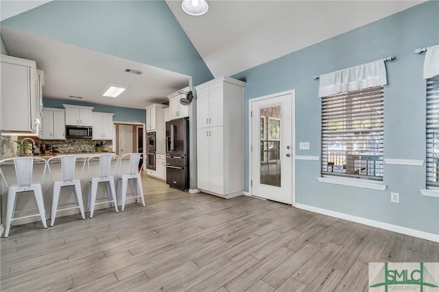 kitchen featuring lofted ceiling, a breakfast bar, kitchen peninsula, high quality fridge, and white cabinetry