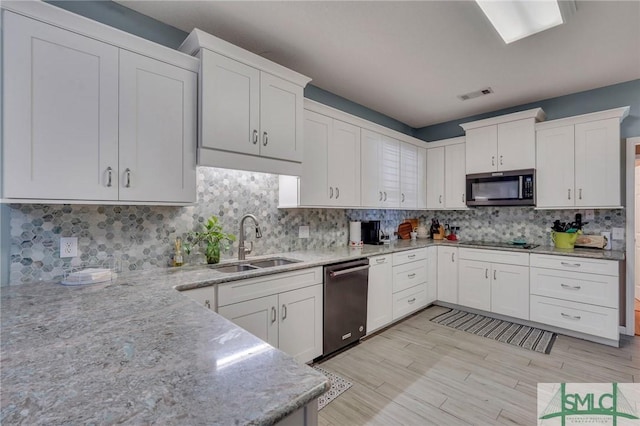 kitchen with stainless steel dishwasher, sink, and white cabinetry