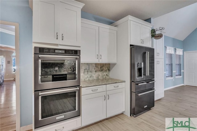 kitchen featuring backsplash, white cabinets, stainless steel double oven, and high end black refrigerator