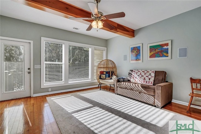 living room featuring ceiling fan, wood-type flooring, and beamed ceiling