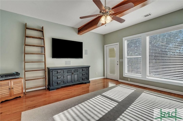 living room featuring ceiling fan, plenty of natural light, hardwood / wood-style flooring, and beam ceiling