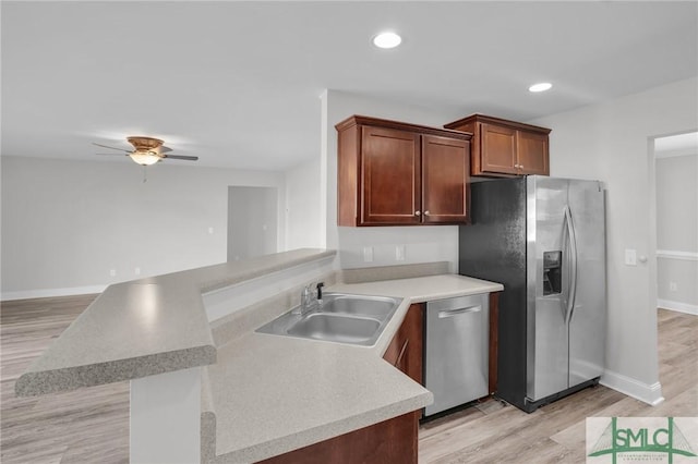 kitchen with stainless steel appliances, sink, kitchen peninsula, light wood-type flooring, and ceiling fan