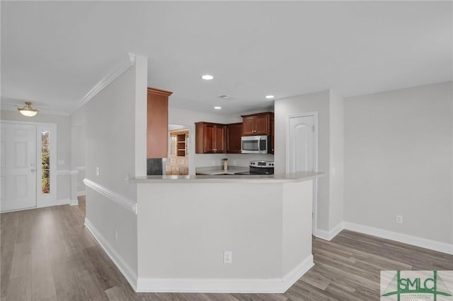 kitchen featuring ornamental molding, stainless steel appliances, kitchen peninsula, and light hardwood / wood-style floors