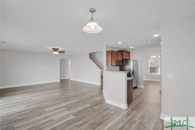 kitchen with ceiling fan with notable chandelier, light hardwood / wood-style floors, hanging light fixtures, and stainless steel fridge with ice dispenser