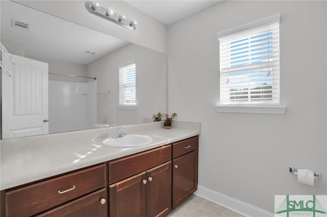 bathroom featuring a wealth of natural light, tile patterned floors, vanity, and walk in shower