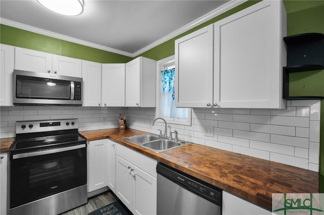 kitchen featuring appliances with stainless steel finishes, wood counters, white cabinetry, sink, and backsplash