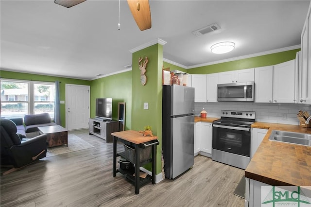 kitchen with wooden counters, white cabinetry, stainless steel appliances, sink, and backsplash