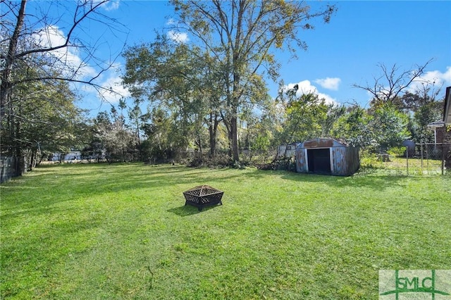 view of yard with a shed and an outdoor fire pit