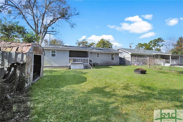 back of property with a fire pit, a storage shed, and a lawn