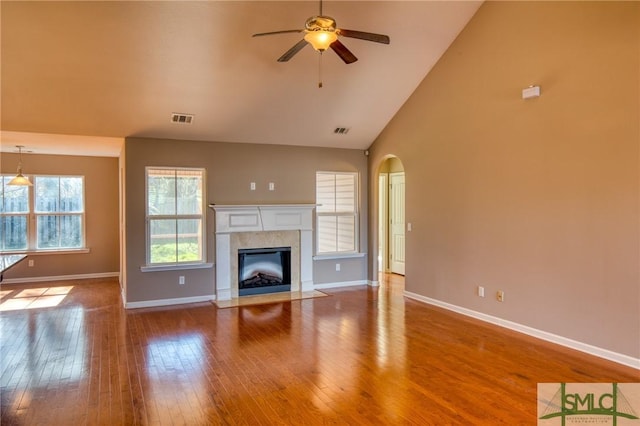 unfurnished living room featuring high vaulted ceiling, wood-type flooring, a tile fireplace, and ceiling fan