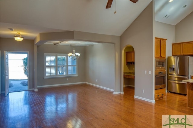 unfurnished living room with ceiling fan with notable chandelier and light wood-type flooring