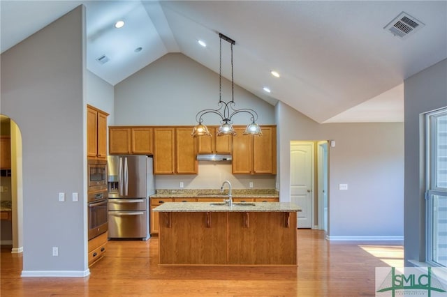 kitchen with sink, hanging light fixtures, a kitchen island with sink, light hardwood / wood-style floors, and stainless steel appliances