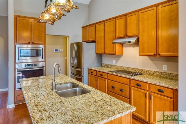 kitchen with light stone counters, sink, a center island with sink, and appliances with stainless steel finishes