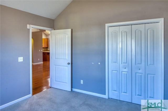 unfurnished bedroom with vaulted ceiling, carpet, and a closet