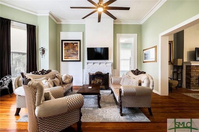 living room with a brick fireplace, hardwood / wood-style floors, crown molding, and ceiling fan