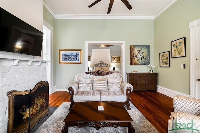 living room featuring ceiling fan, crown molding, dark hardwood / wood-style floors, and a brick fireplace