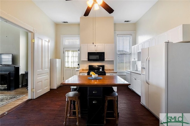 kitchen with dark hardwood / wood-style floors, a center island, black appliances, a breakfast bar, and white cabinets