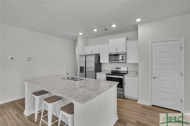 kitchen with light hardwood / wood-style floors, sink, white cabinetry, a kitchen island with sink, and appliances with stainless steel finishes