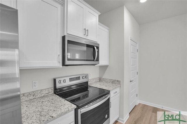 kitchen with white cabinets, light wood-type flooring, light stone counters, and stainless steel appliances