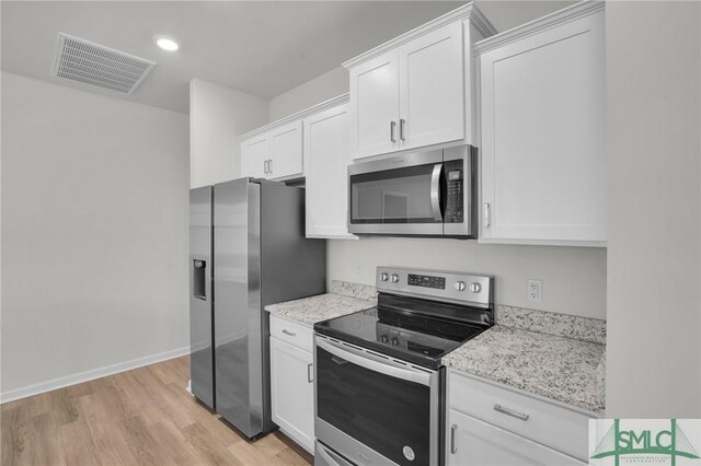 kitchen with light hardwood / wood-style floors, light stone counters, stainless steel appliances, and white cabinetry