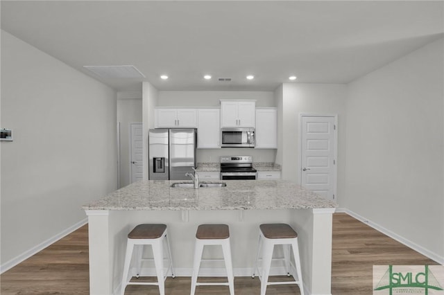 kitchen featuring stainless steel appliances, sink, white cabinets, and an island with sink