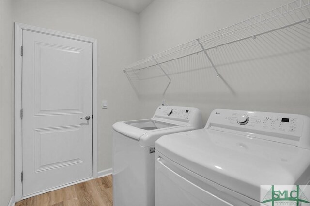 clothes washing area featuring light wood-type flooring and separate washer and dryer