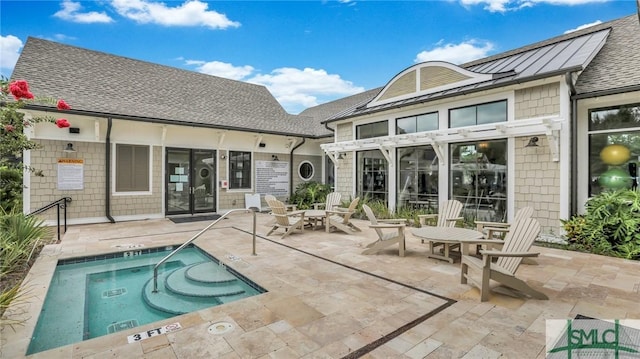 back of property with a hot tub and a patio