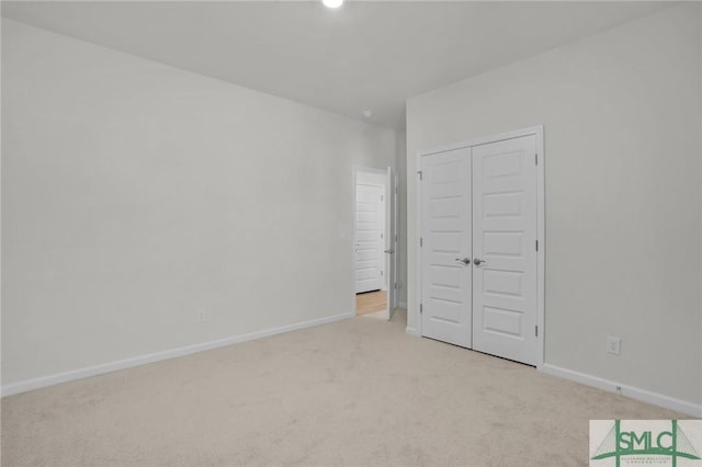 unfurnished bedroom featuring light colored carpet and a closet