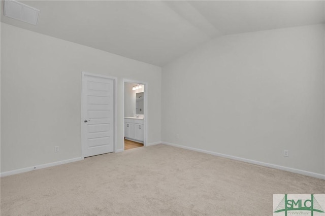 unfurnished bedroom with ensuite bathroom, lofted ceiling, and light carpet