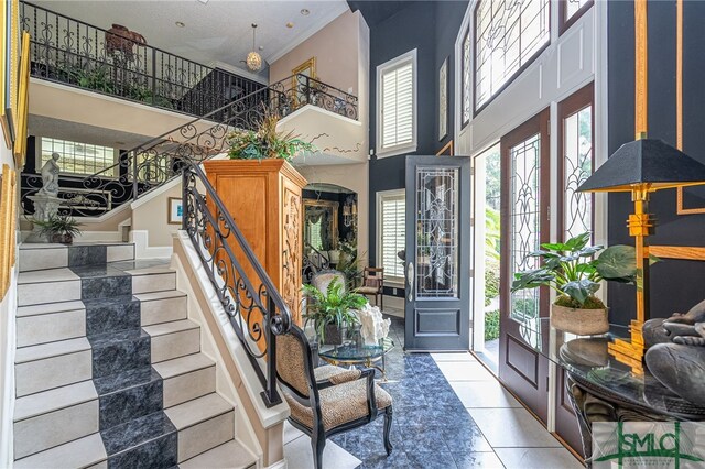 tiled foyer entrance featuring stairs, a high ceiling, and arched walkways