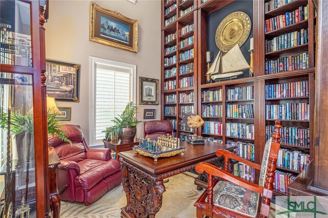 home office featuring bookshelves and a towering ceiling