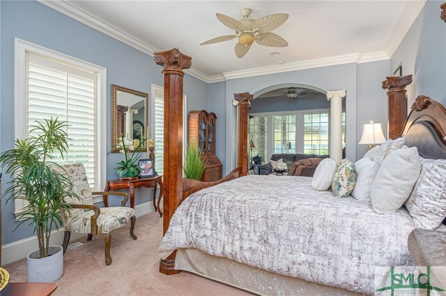 carpeted bedroom featuring crown molding, multiple windows, decorative columns, and a ceiling fan