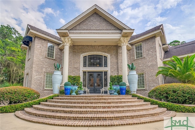 view of exterior entry with brick siding and french doors