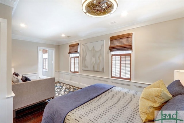 bedroom featuring crown molding, hardwood / wood-style floors, and multiple windows