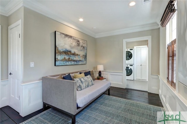 living room featuring crown molding, a healthy amount of sunlight, dark hardwood / wood-style floors, and stacked washing maching and dryer